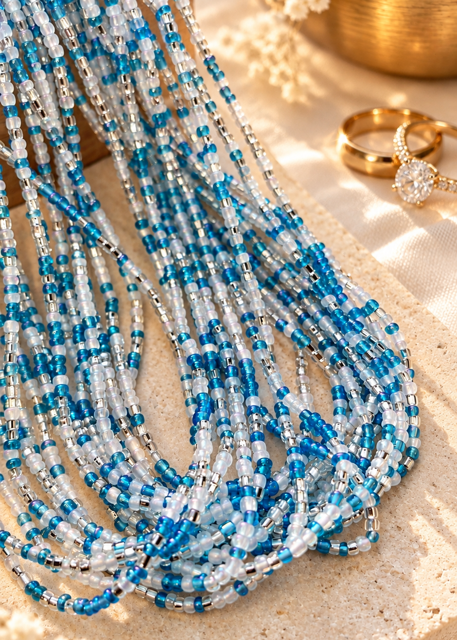 Something Blue waist beads in iridescent blue, white, and silver arranged on a textured surface