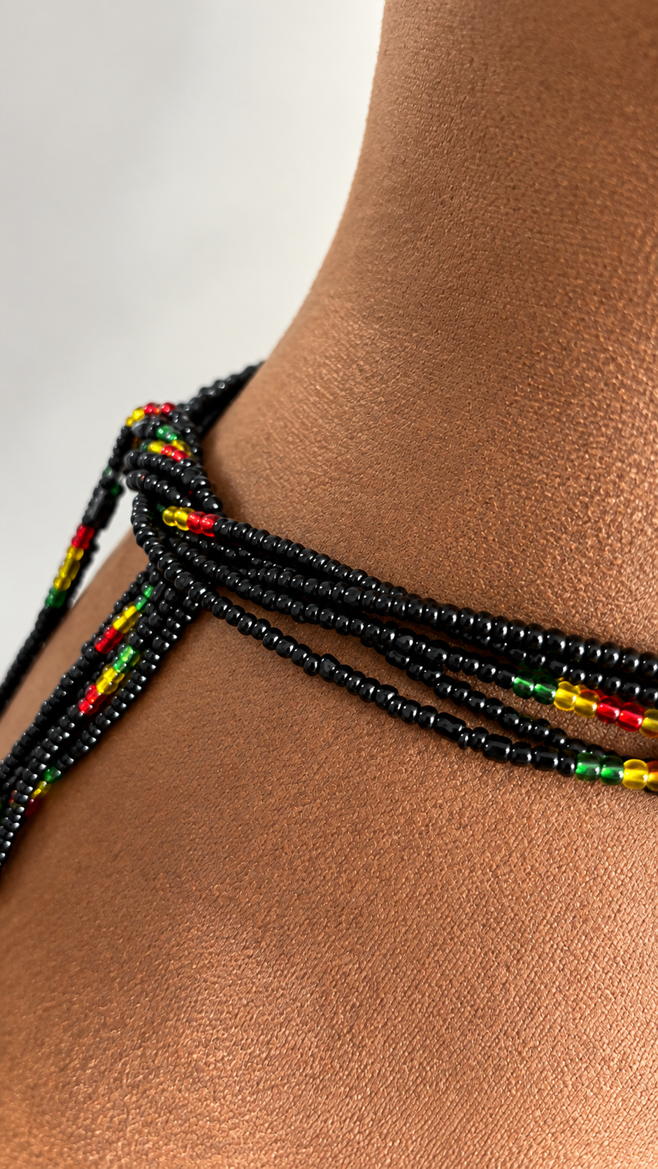 Close-up of Live Ghana black waist beads with red, gold, and green accents tied around the waist