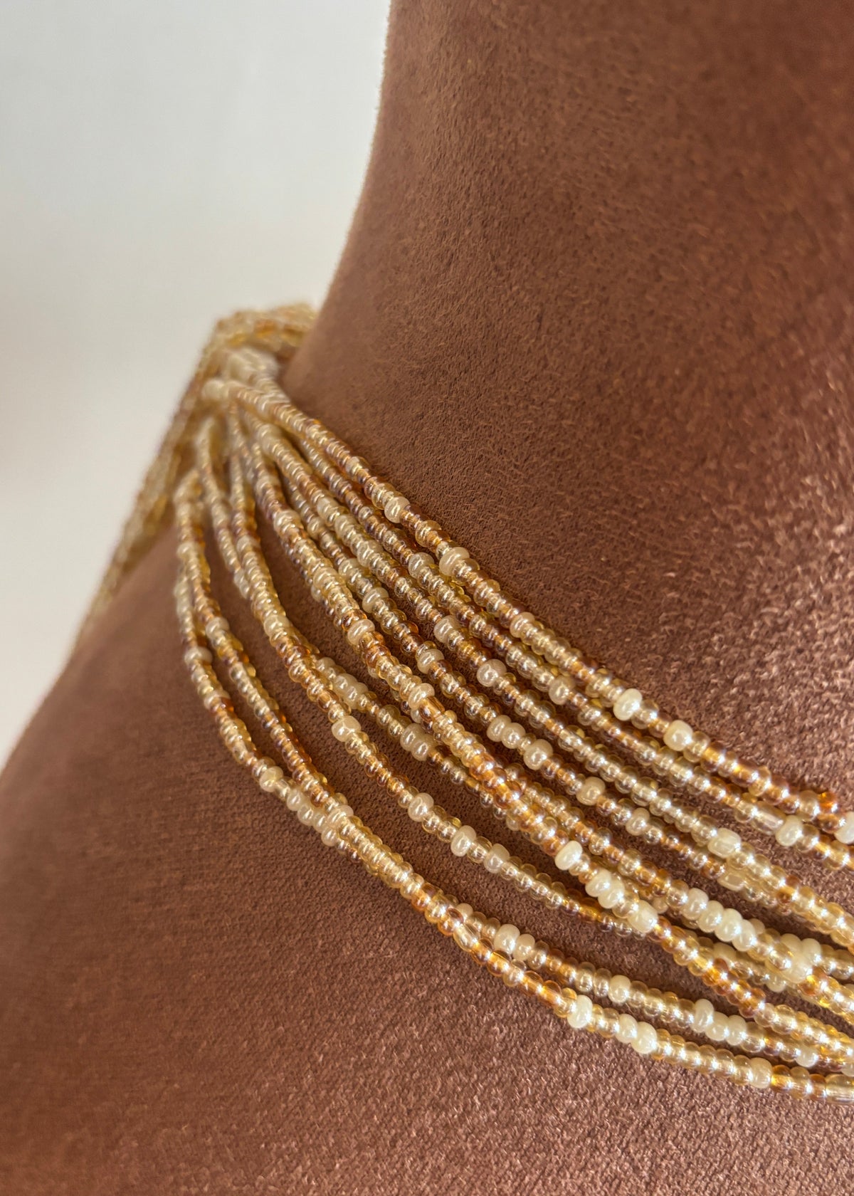 Close-up of Empress champagne, amber, and pearl ivory waist beads worn at the waist