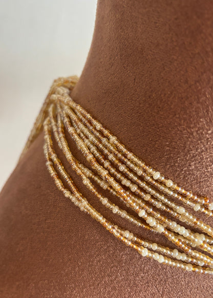 Close-up of Empress champagne, amber, and pearl ivory waist beads worn at the waist