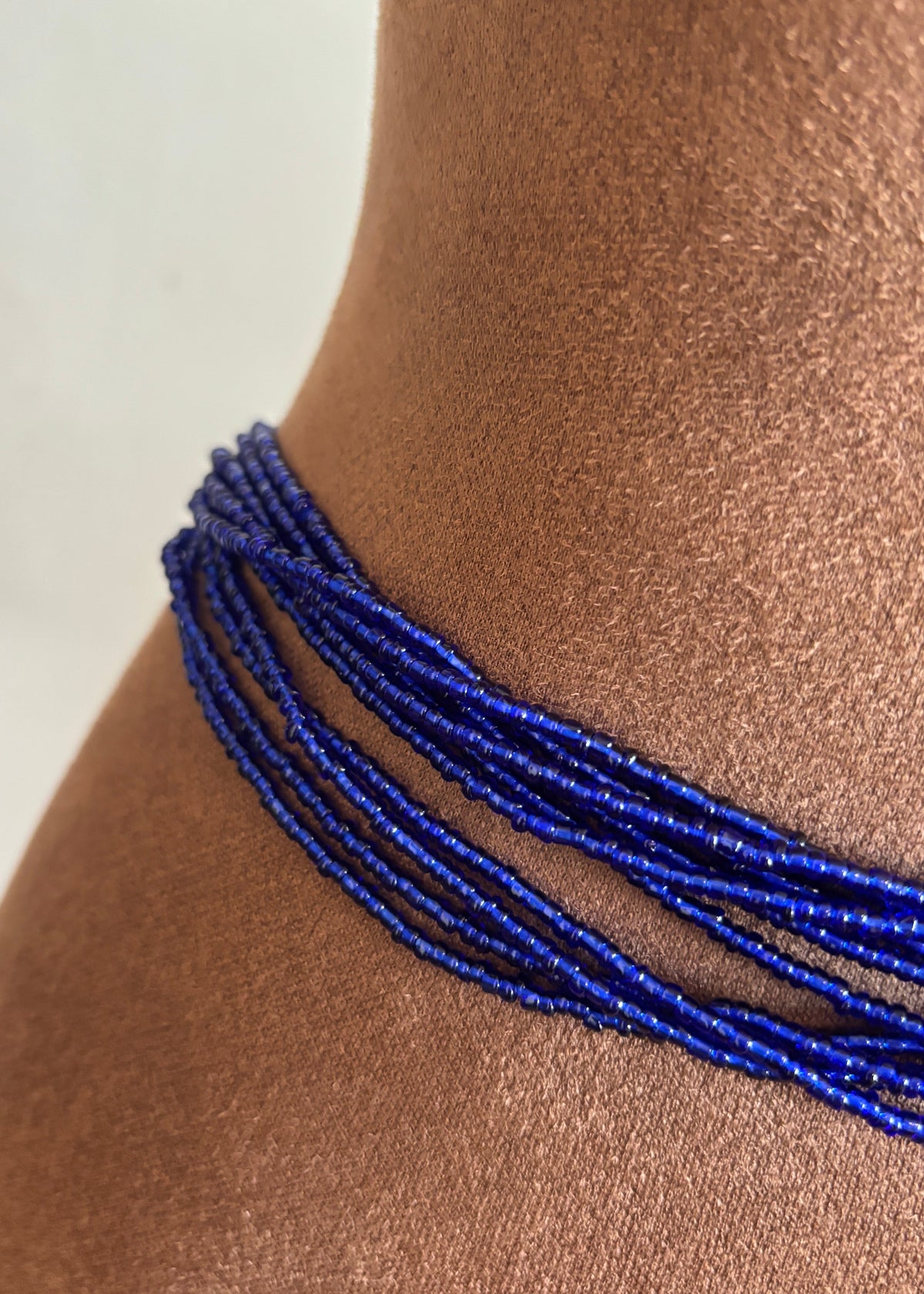 Close-up of blue Riviera waist beads on a display form