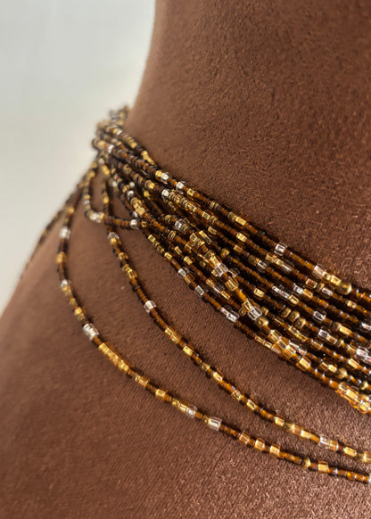 Close-up of Crowned brown and metallic glass waist beads draped over a brown display form