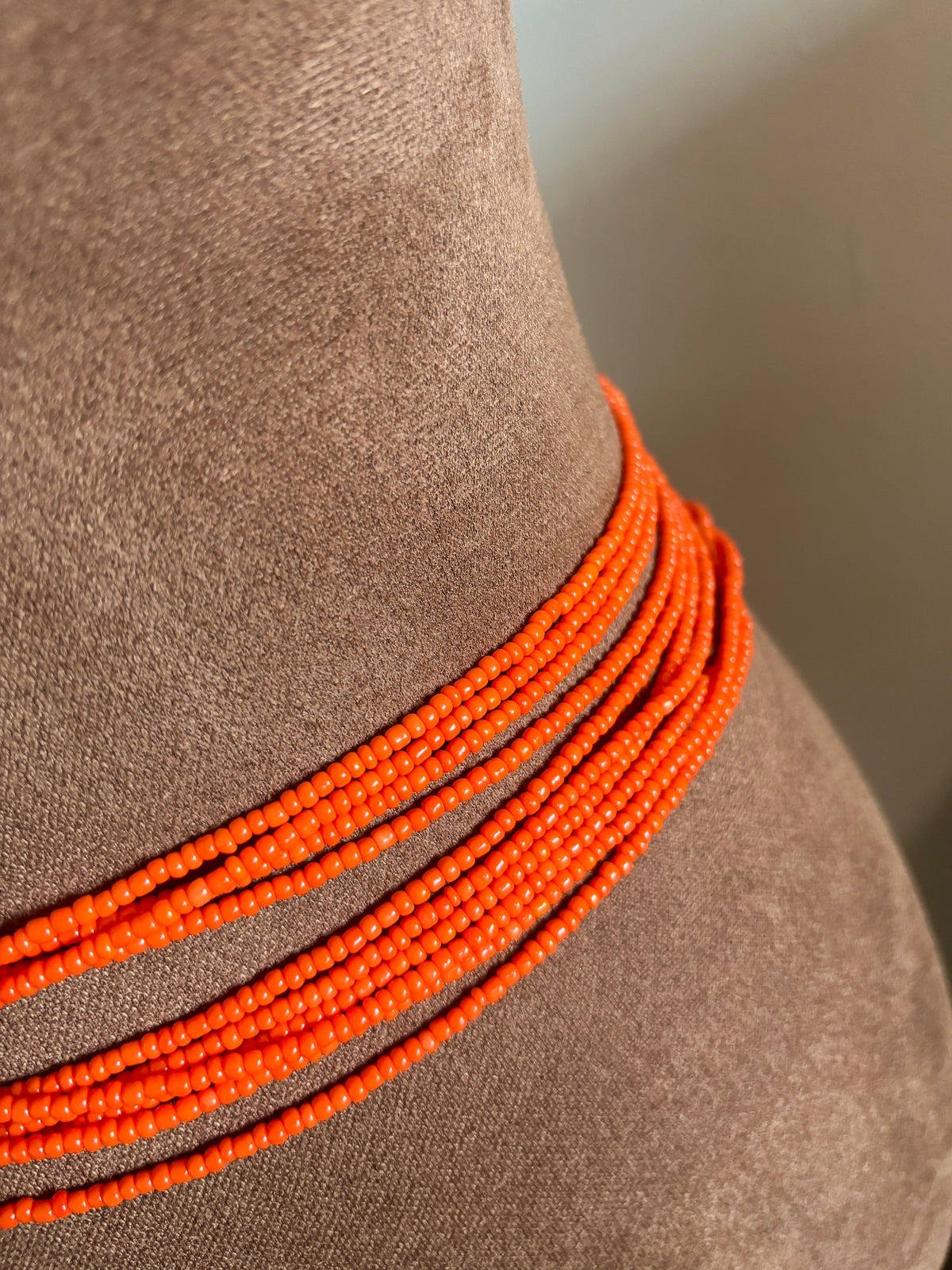Close-up of multiple orange Zinnia waist bead strands worn around the waist.