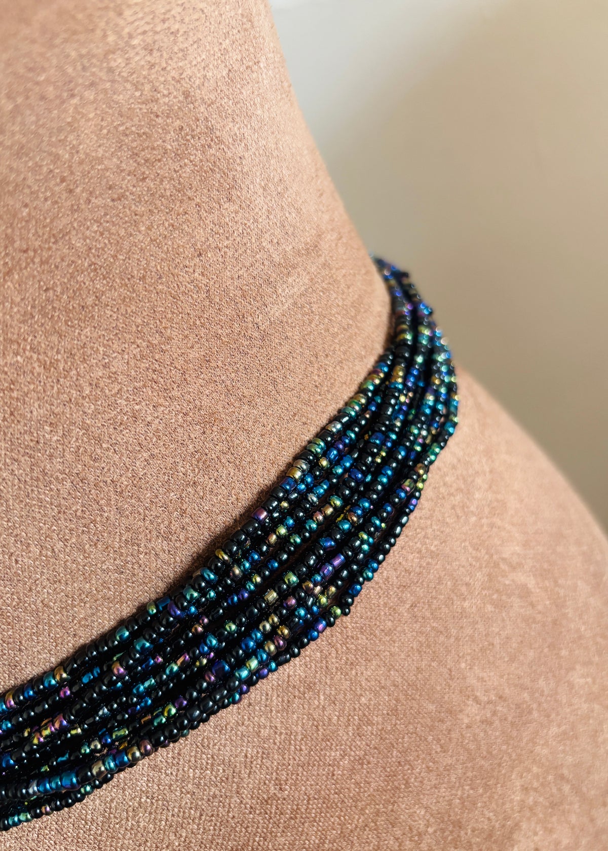 Close-up of Black Girl Magic waist beads showing black and iridescent jewel-toned beads against skin