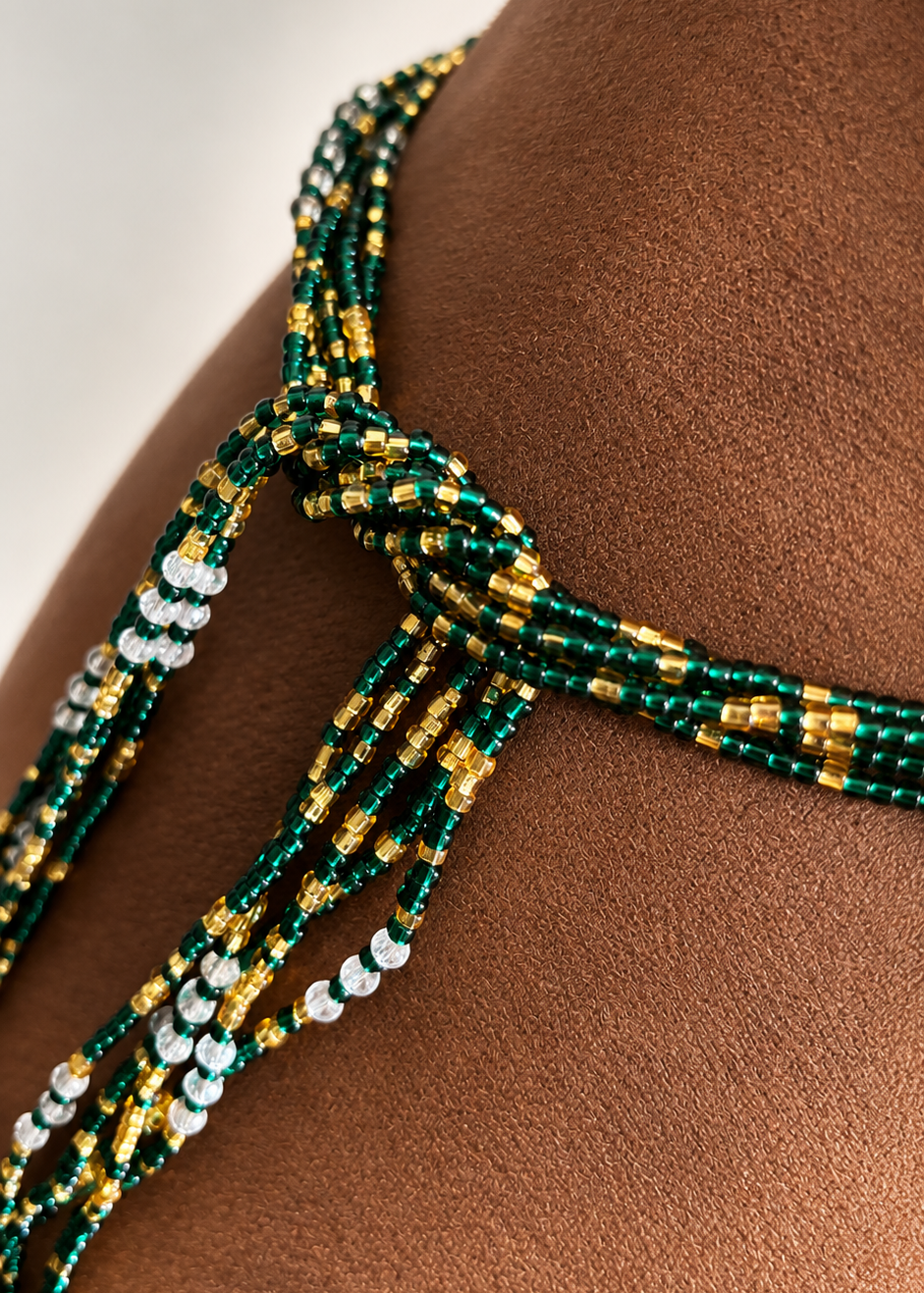 Close-up of the tie on Emerald Dynasty Luxe waist beads with green, gold, and iridescent accents