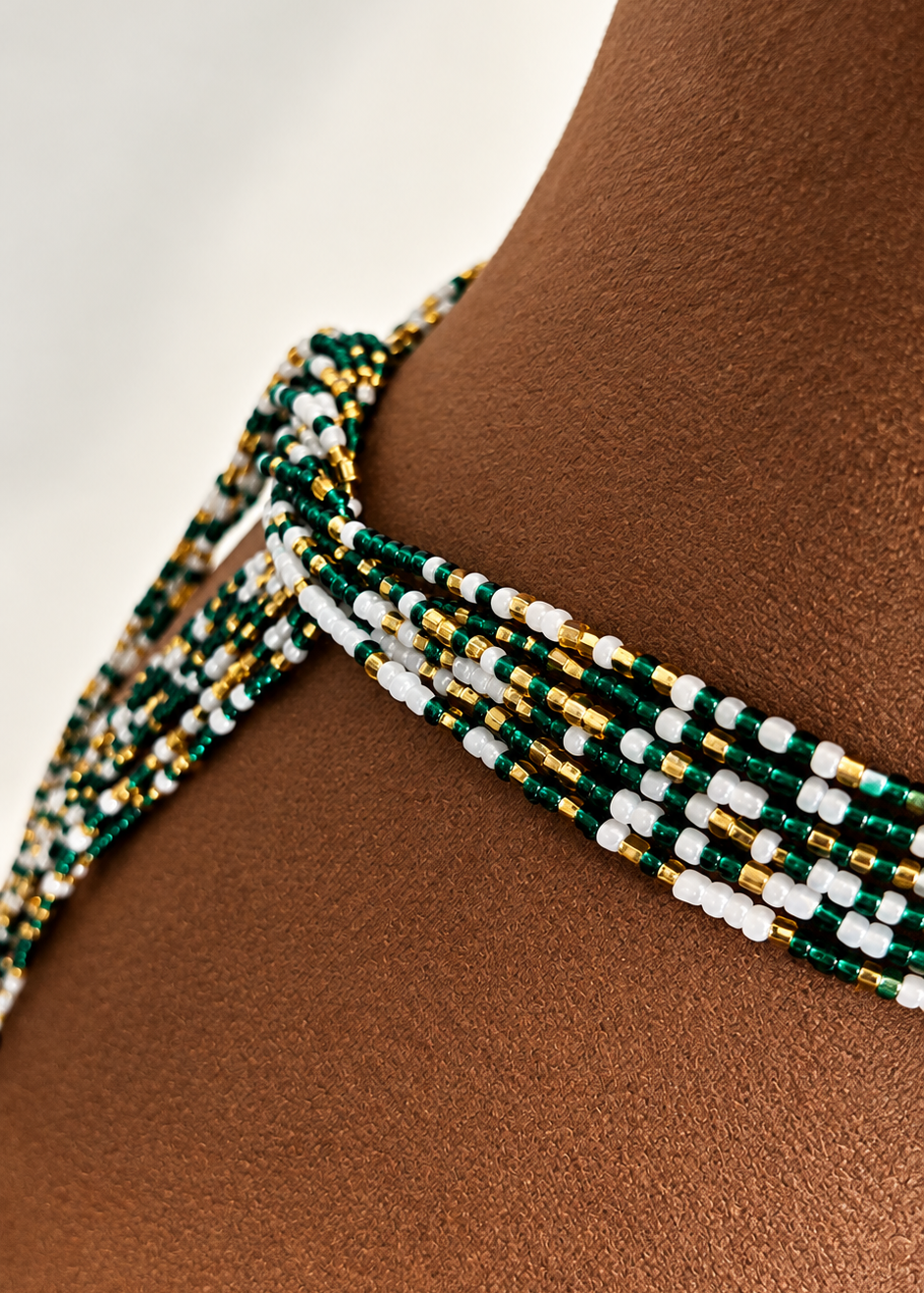 Close-up of Emerald Dynasty Pearl green, gold, and pearl white beads tied around the waist