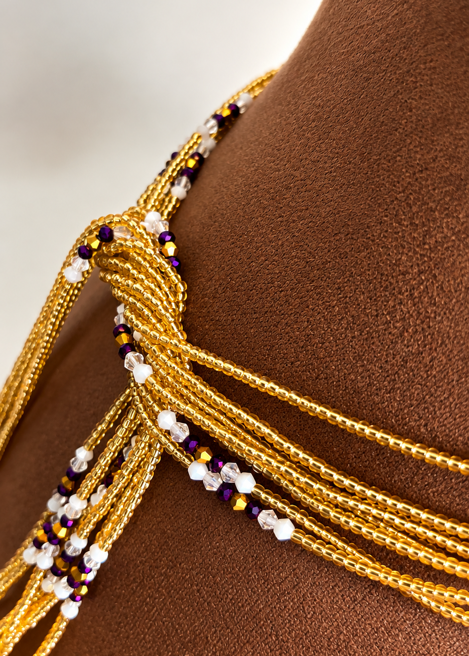 Close-up of The Matriarch Luxe waist beads with gold strands and purple crystal accents