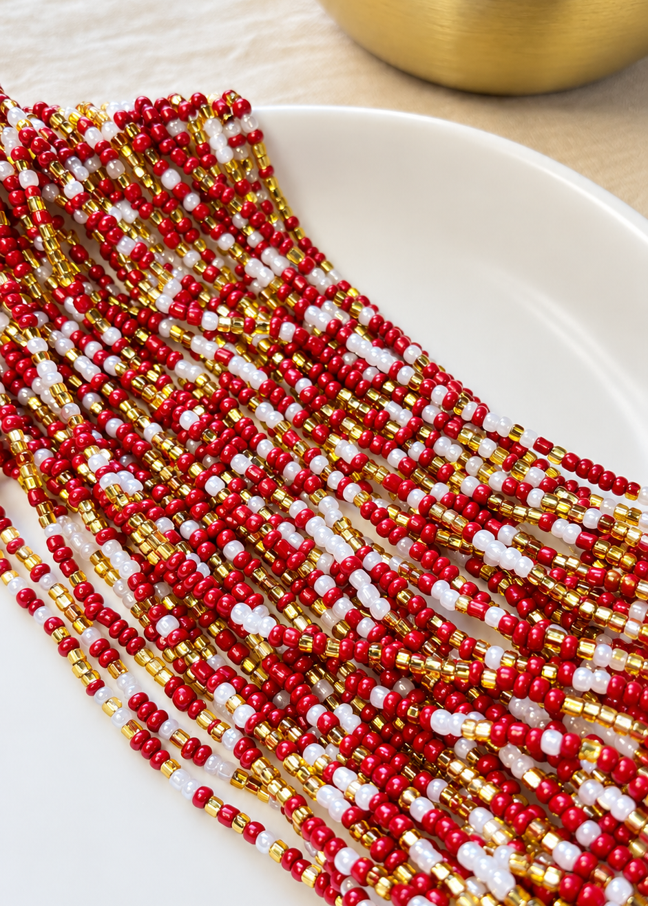 Lover Girl red, gold, and pearl white waist beads arranged on a white dish
