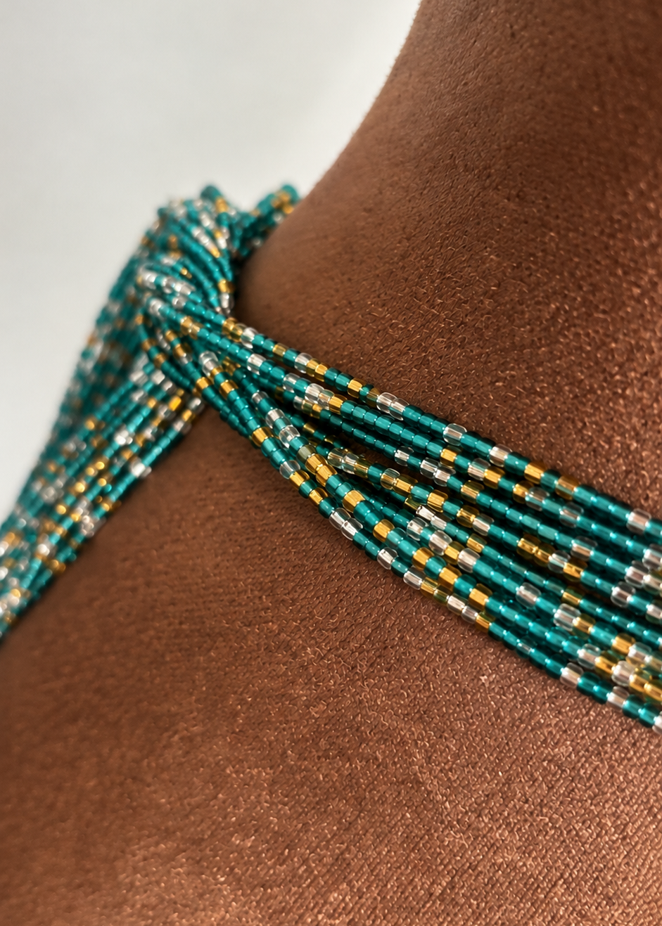 Close-up of aqua, gold, and silver Ocean Glow waist beads worn on the waist