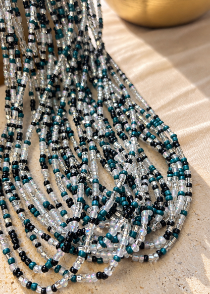 Midnight Rain waist beads in teal, black, clear, and iridescent white arranged flat