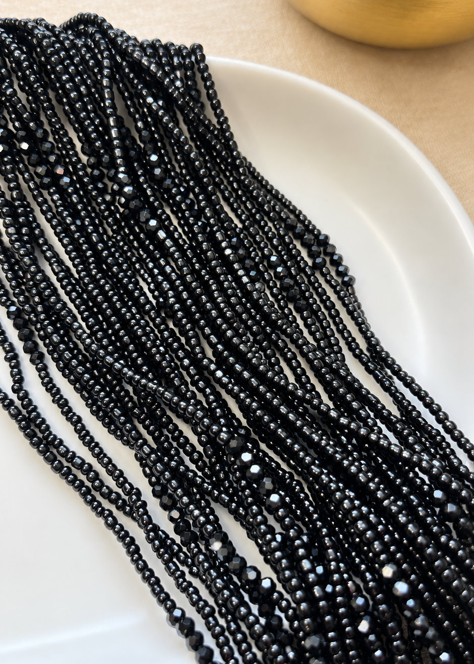 Black Obaa Tuntum Luxe waist beads with faceted crystal accents arranged on a dish