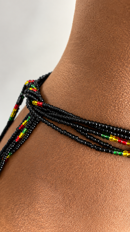 Close-up of Live Ghana black waist beads with red, gold, and green accents tied around the waist