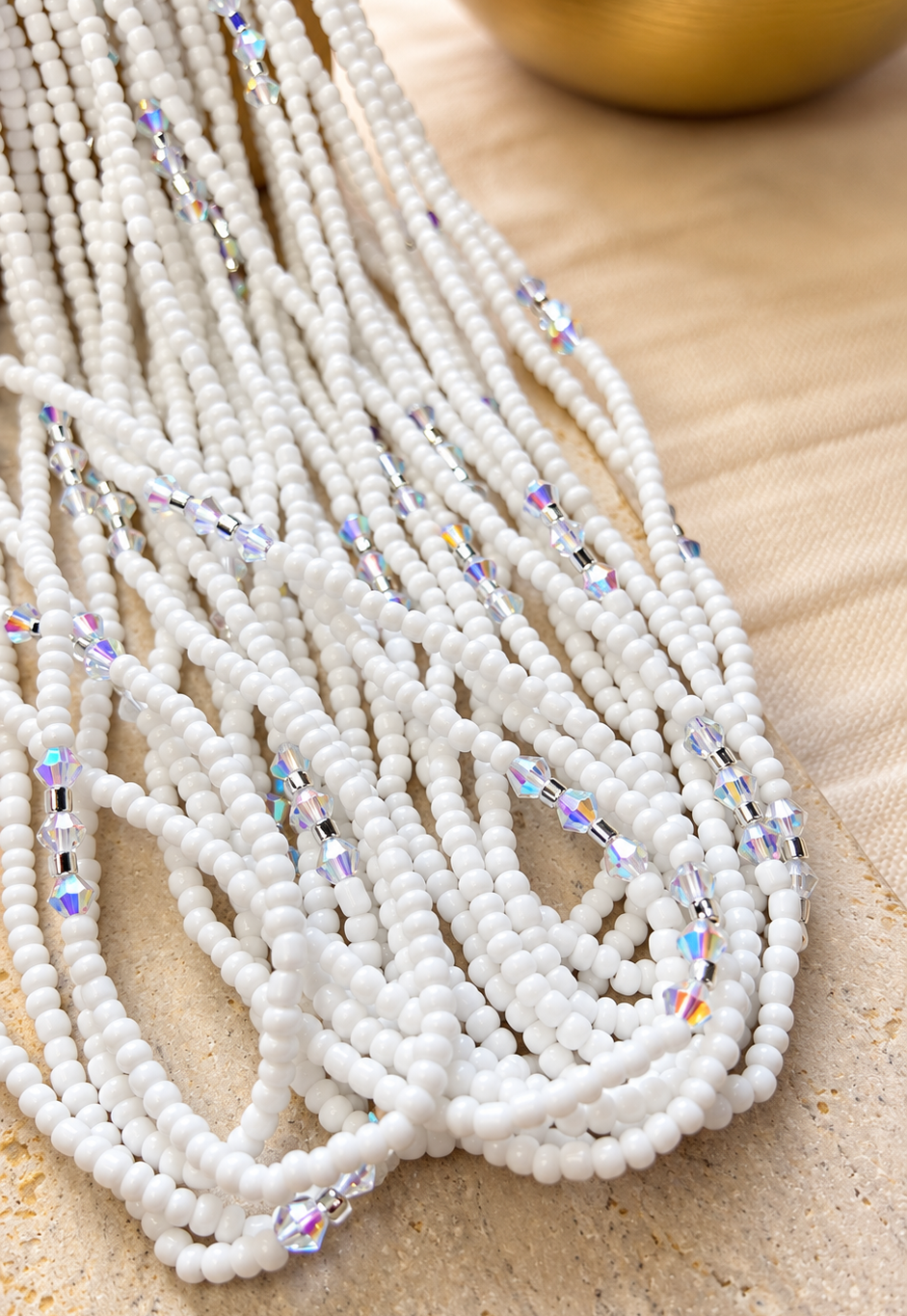 Crystal Whisper white glass waist beads with iridescent crystal accents arranged on beige fabric
