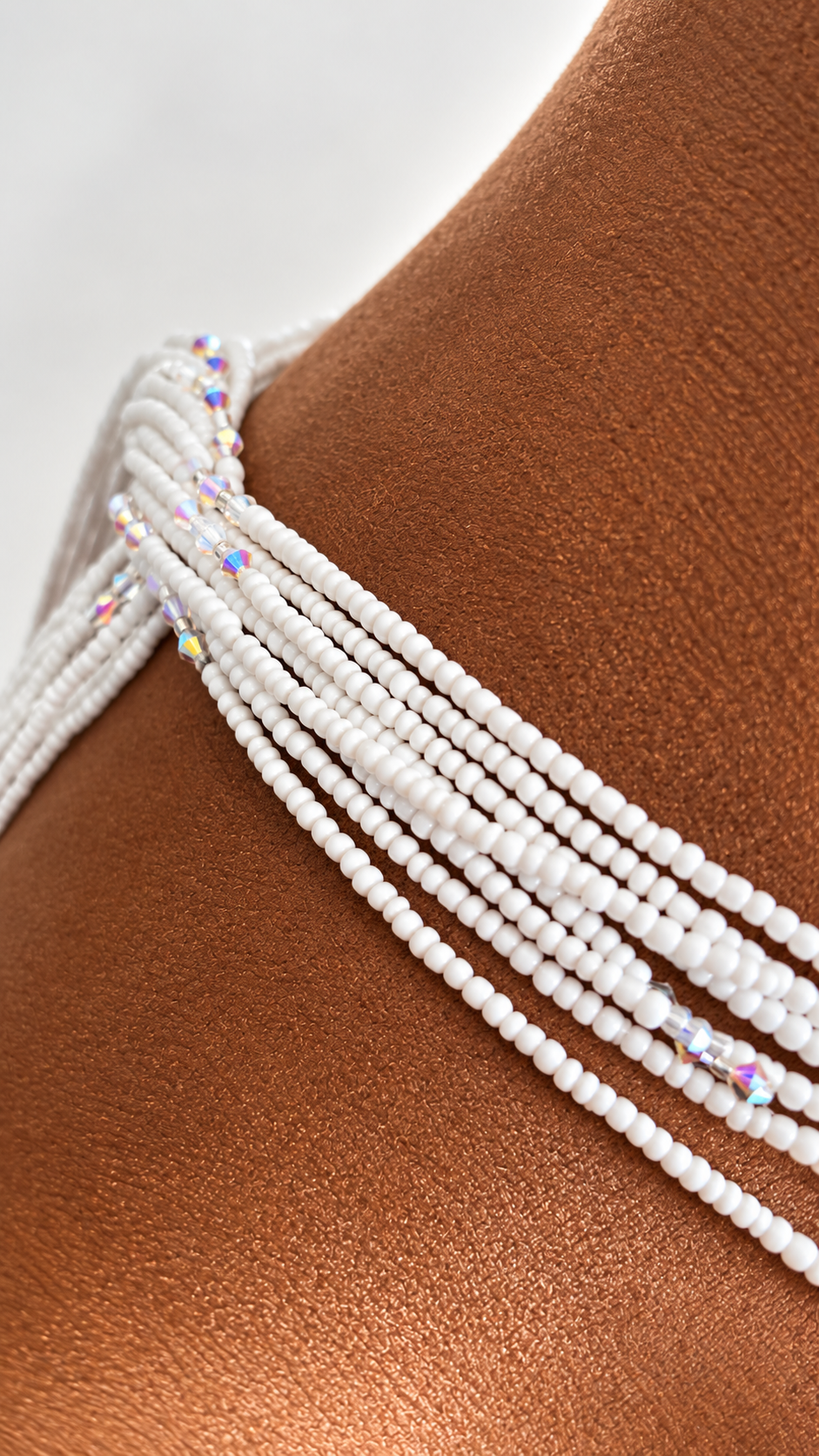 Close-up of Crystal Whisper white waist beads with iridescent crystal accents worn over a brown display form