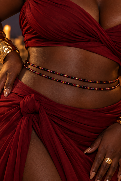 Close-up of Gracious Goddess black, red, and gold waist beads worn with a burgundy outfit
