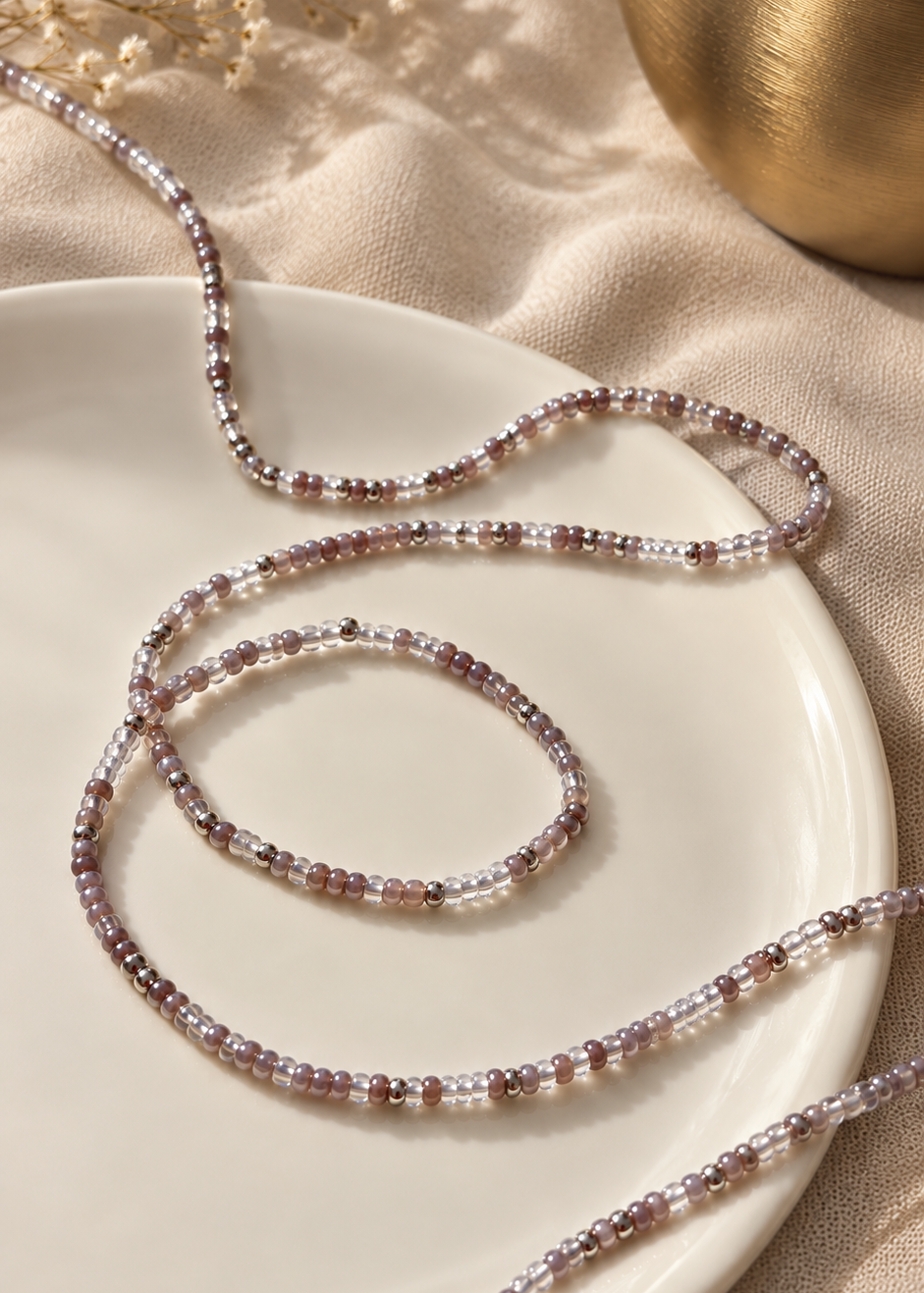 Heaven gray, clear, and silver waist beads arranged in a loop on a dish