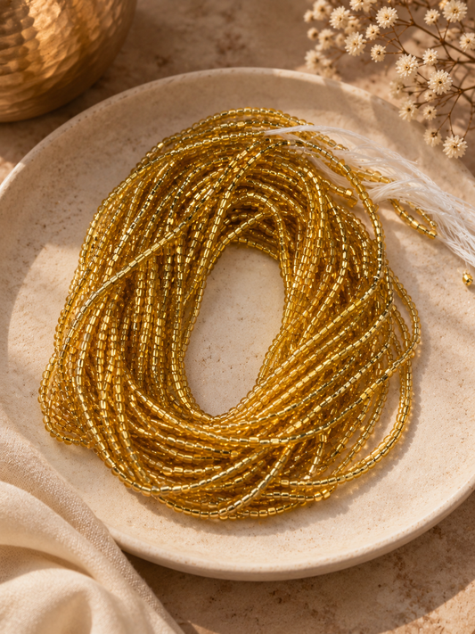 Gold Sika waist beads arranged in a shallow stone dish