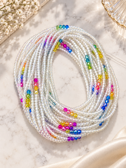White Unicorn waist beads with a soft white iridescent finish and rainbow crystal accents, coiled on a light surface.