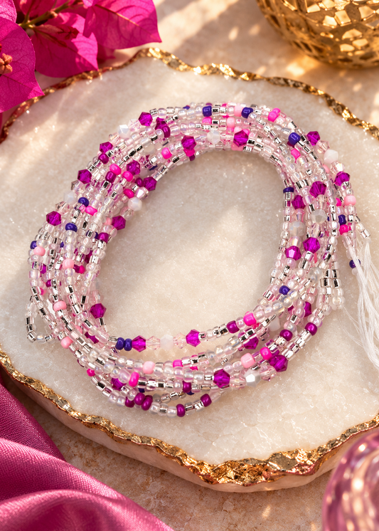 Pink Reign Luxe waist beads in pink, fuchsia, purple, and clear tones arranged on a dish
