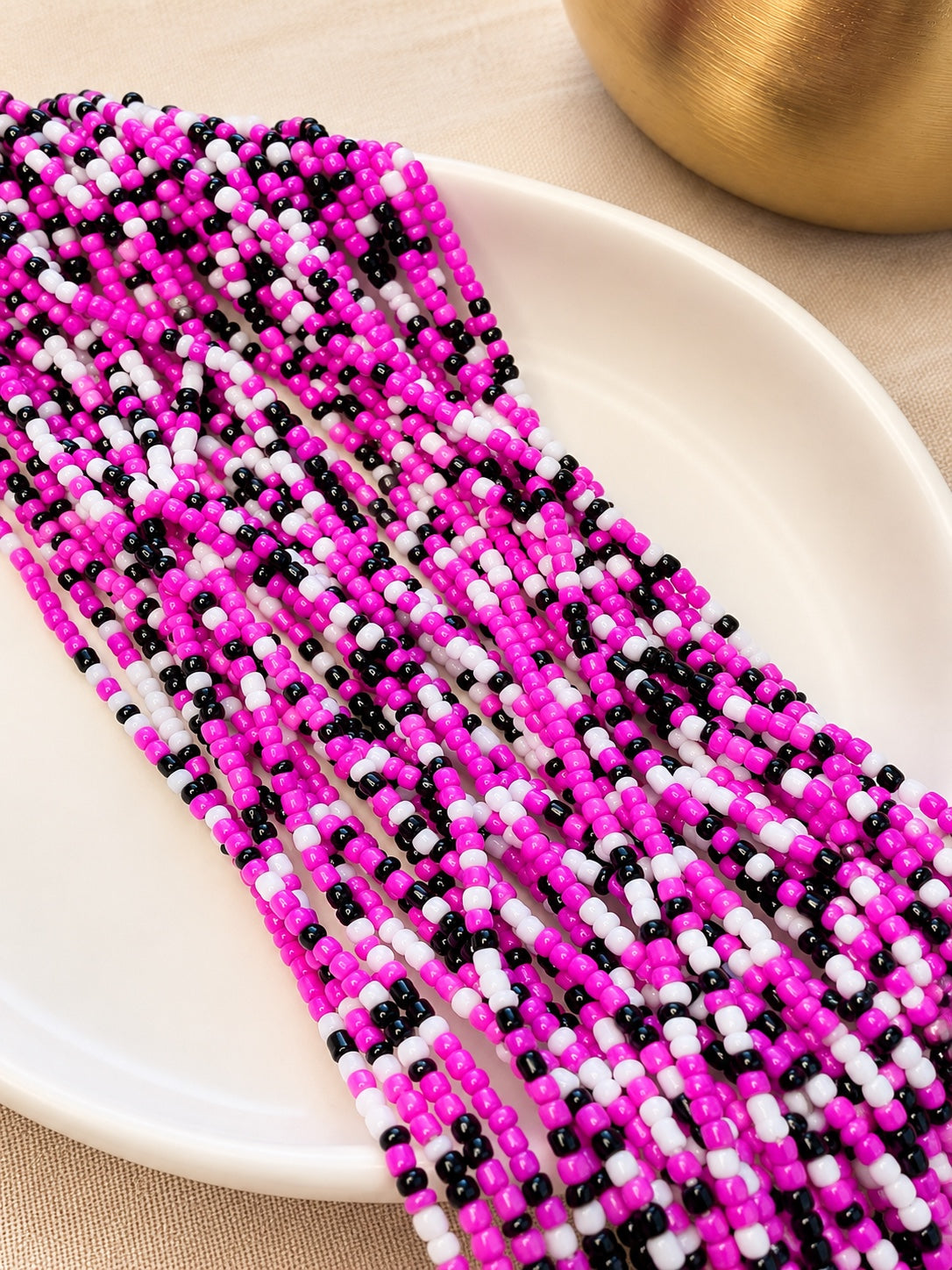 Charisma hot pink, black and white tie-on waist beads arranged on an ivory dish