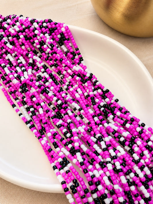 Charisma hot pink, black and white tie-on waist beads arranged on an ivory dish